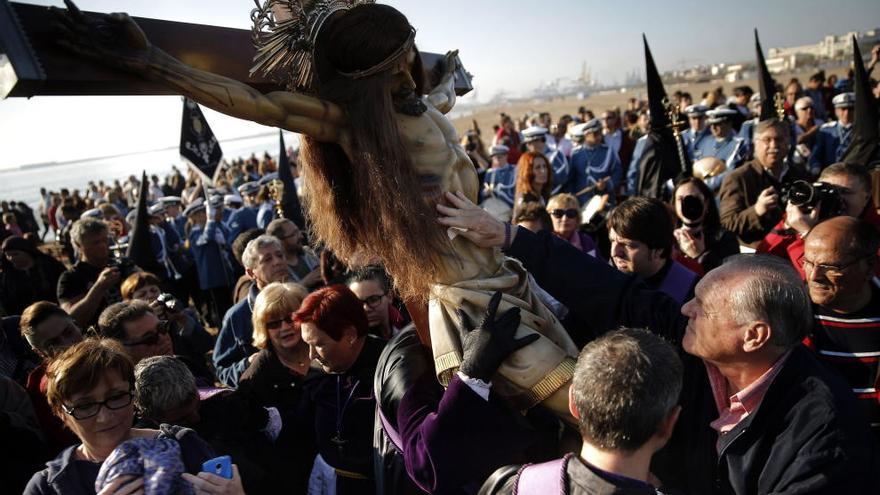 Un fiel acaricia la imagen de Cristo durante el Viernes Santo en la procesión a la playa.