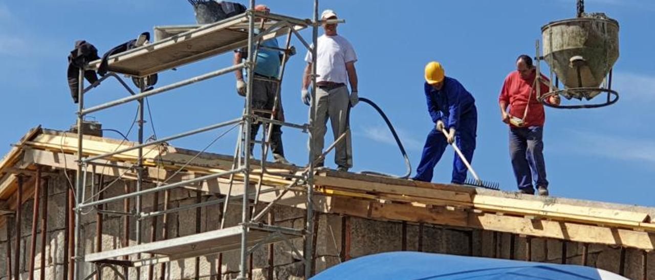 Trabajadores hormigonando el tejado de una casa en construcción.