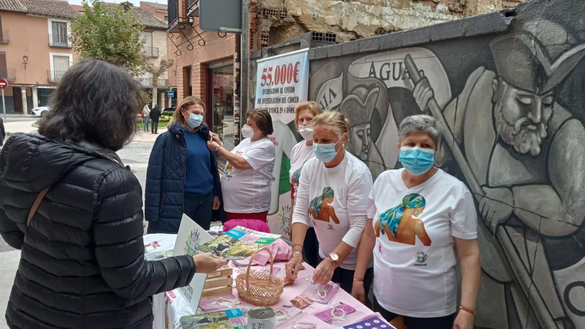 Voluntarias de la asociación entregan lazos en la mesa informativa instalada en Toro