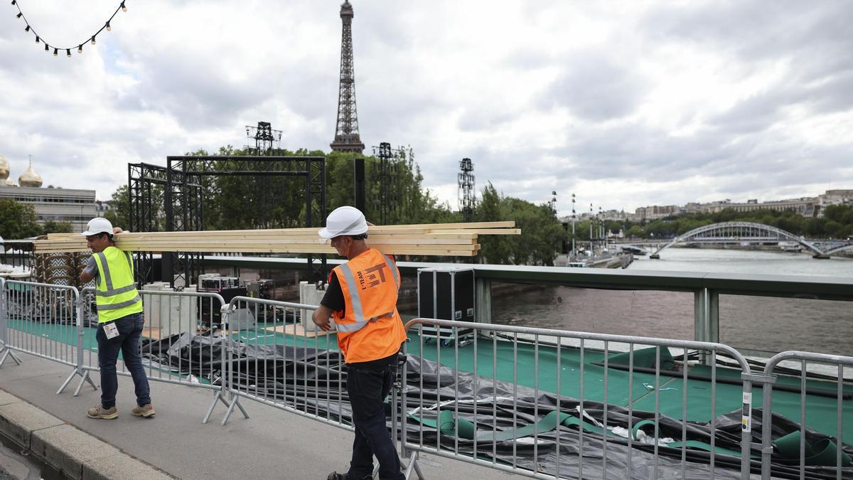 Varios operarios pasan ante el río Sena de París, el martes 23 de julio.