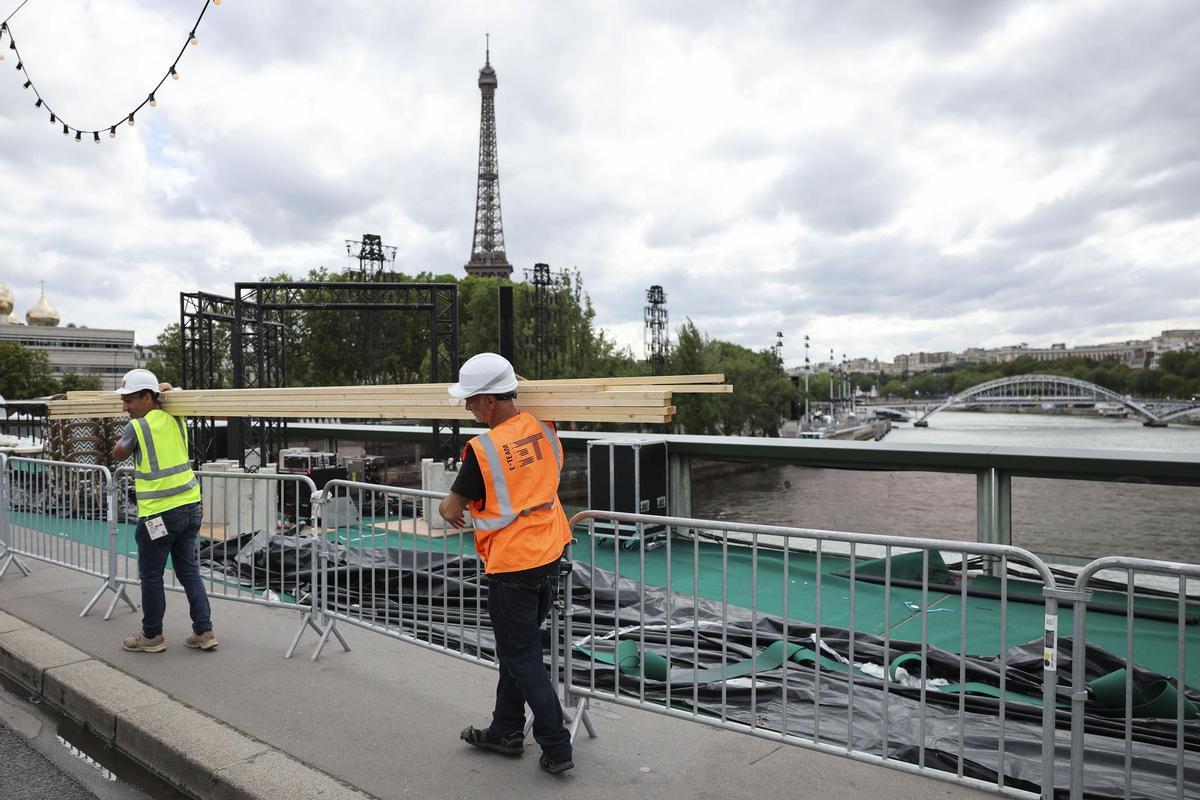 Varios operarios pasan ante el río Sena de París, el martes 23 de julio.