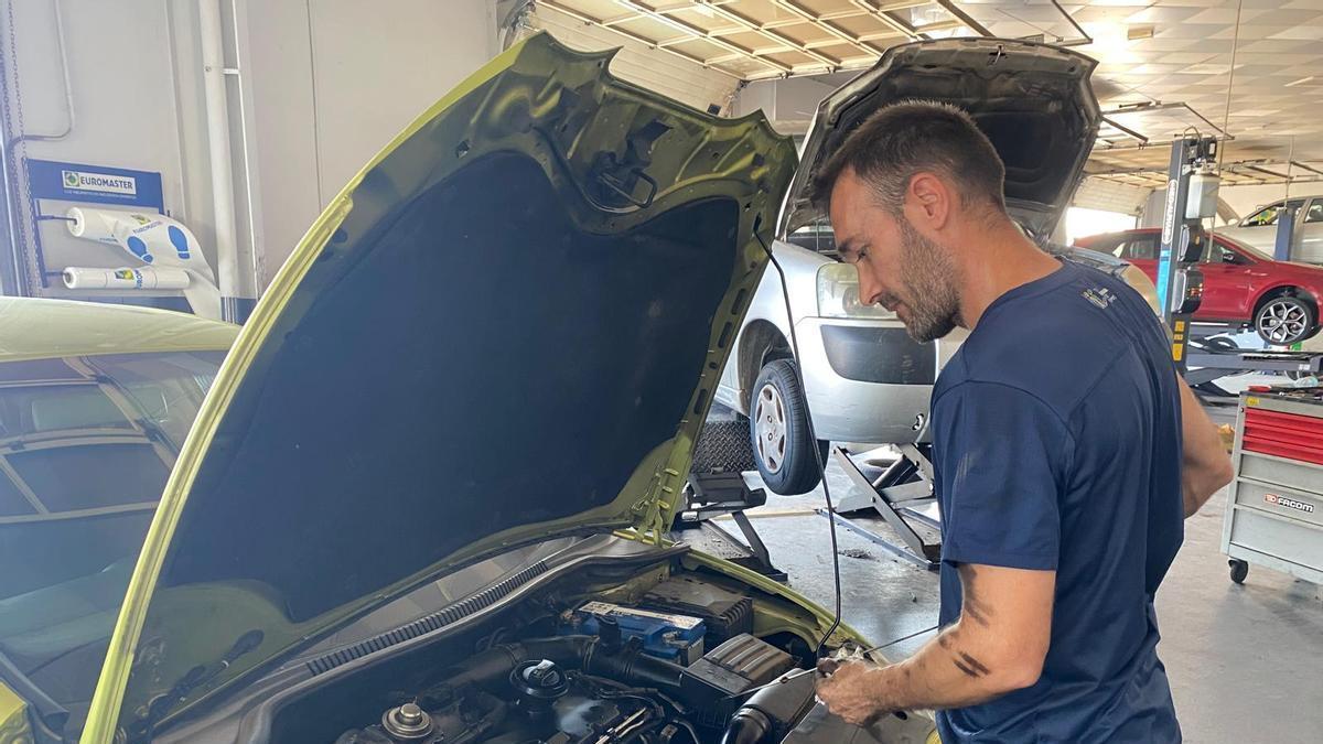 Un mecánico trabaja en un coche en reparación dentro de un taller de Castelló.