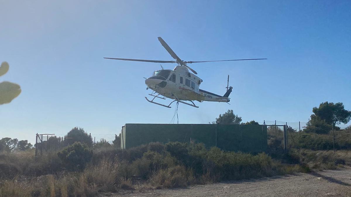 Un helicóptero recarga el tanque de agua en una balsa de riego