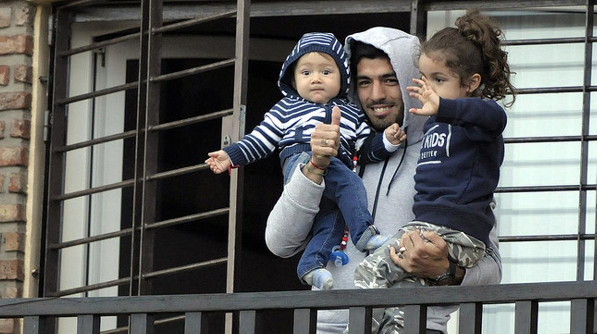 Luis Suárez, acompanyat dels seus fills, saluda els aficionats des del balcó de casa seva a Montevideo. Luis Suárez, acompanyat dels seus fills, saluda els aficionats des del balcó de casa seva a Montevideo.