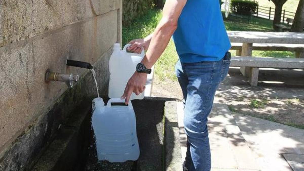Una persona omplint dues garrafes d'aigua