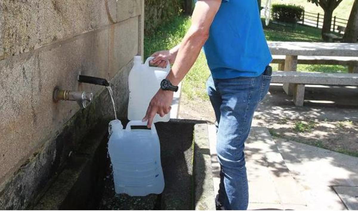 Una persona omplint dues garrafes d'aigua