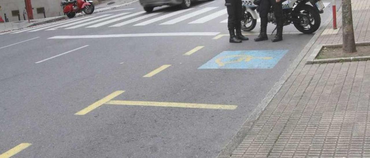 Policías locales, ayer, ante dos plazas de estacionamiento para minusválidos en A Ponte. // Iñaki Osorio