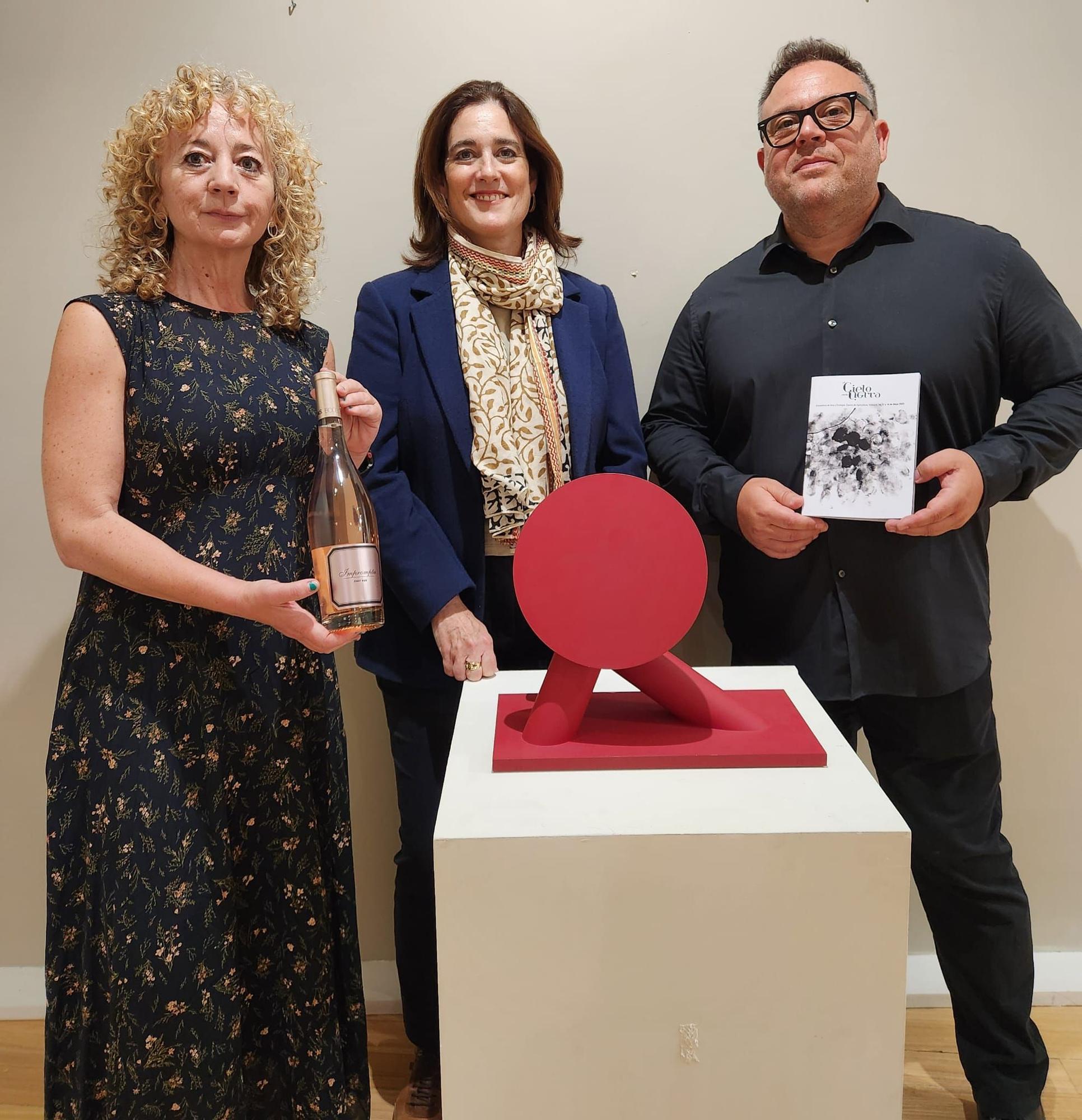 Rosa Vázquez, gerente PROAVA, Ana Ibáñez, gerente del Casino de Agricultura y Samuel Casavella, comisario de la exposición, con la obra de Miguel Navarro y una botella de Tamtun Rose..jpg