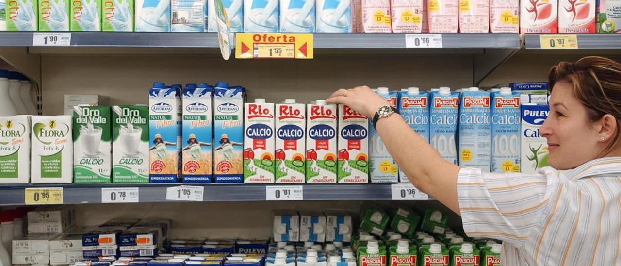 Una empleada de un supermercado señala envases de leche // FARO