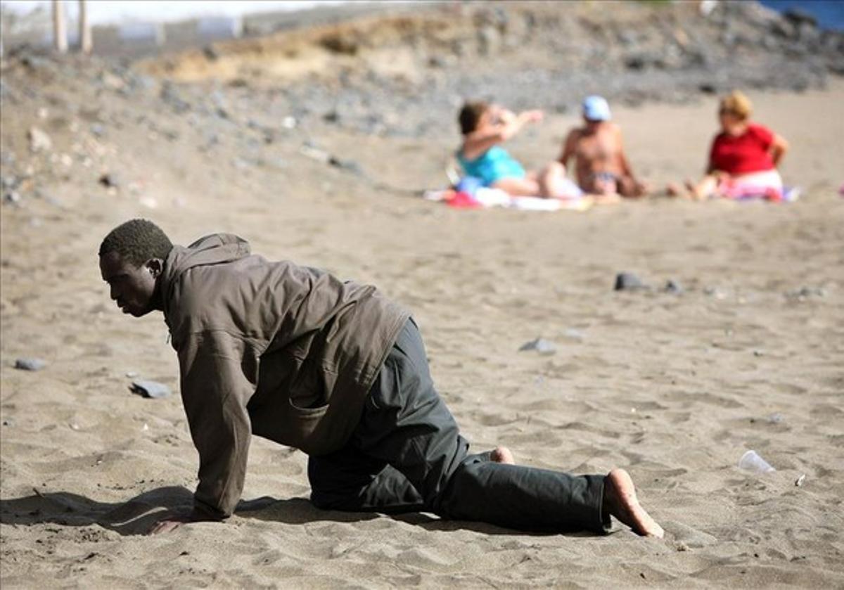 A would-be immigrant crawls on the beach after his arrival on a makeshift boat on the Gran Tarajal beach in Spain’s Canary Island of Fuerteventura in this May 5, 2006 file photo.