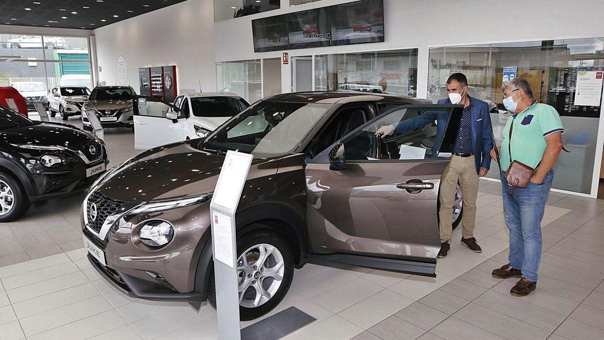 Clientes examinan un coche en un concesionario.