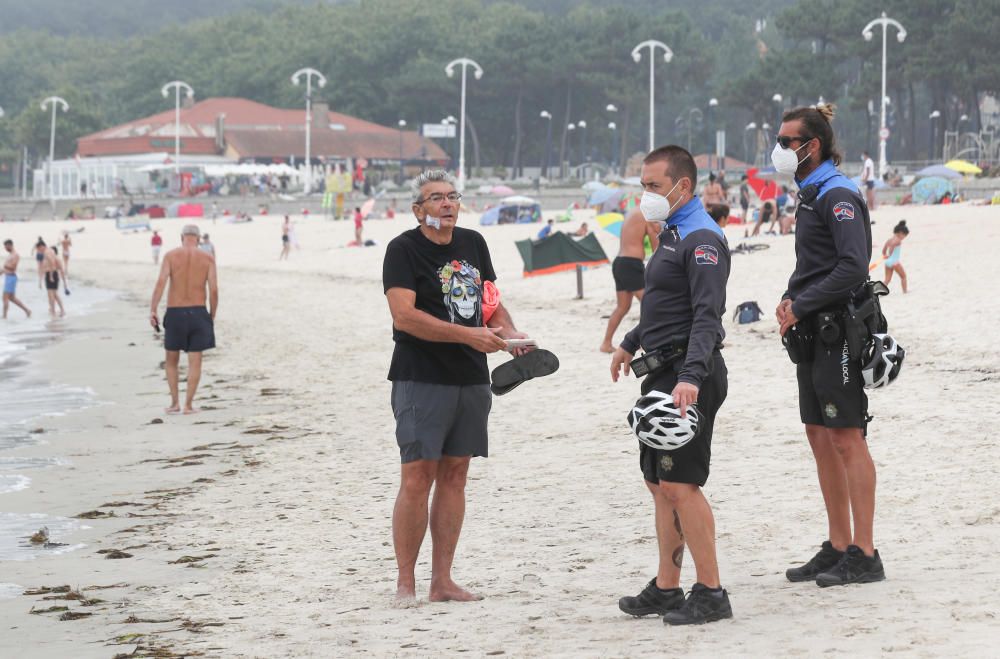 Los vigueses estrenan  las mascarillas obligatorias en Galicia en la playa y en medio de la niebla