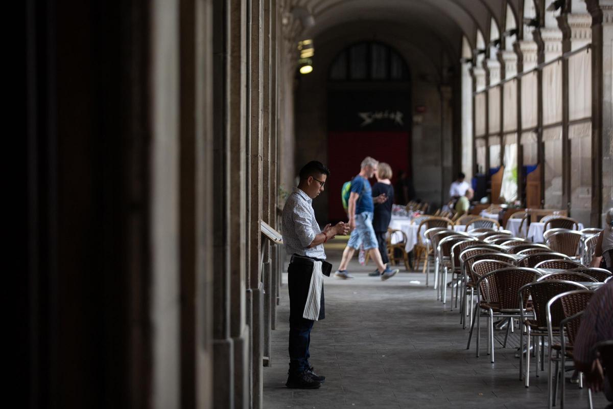 Un camarero esperando clientes en la terraza de un bar de Barcelona