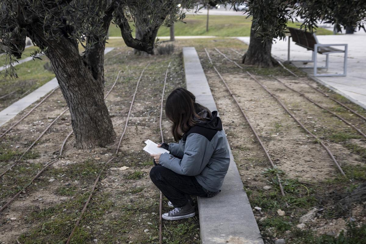 Una chica joven leyendo en un parque.