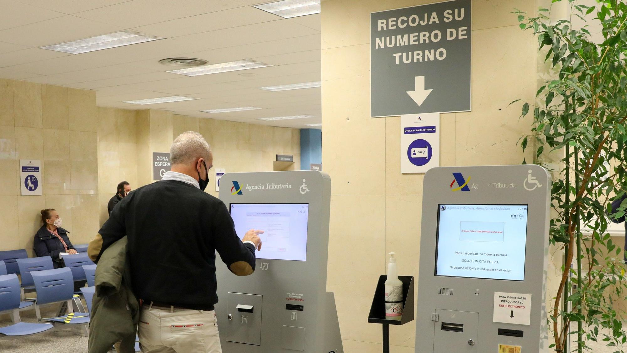 Un hombre recoge su turno en una oficina de la Agencia Tributaria de Madrid durante la campaña de la renta del año pasado.