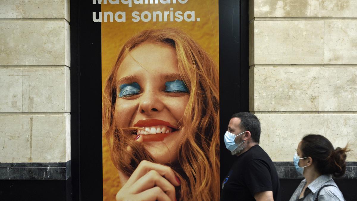 Dos personas pasan delante de una tienda de cosmética en Murcia.