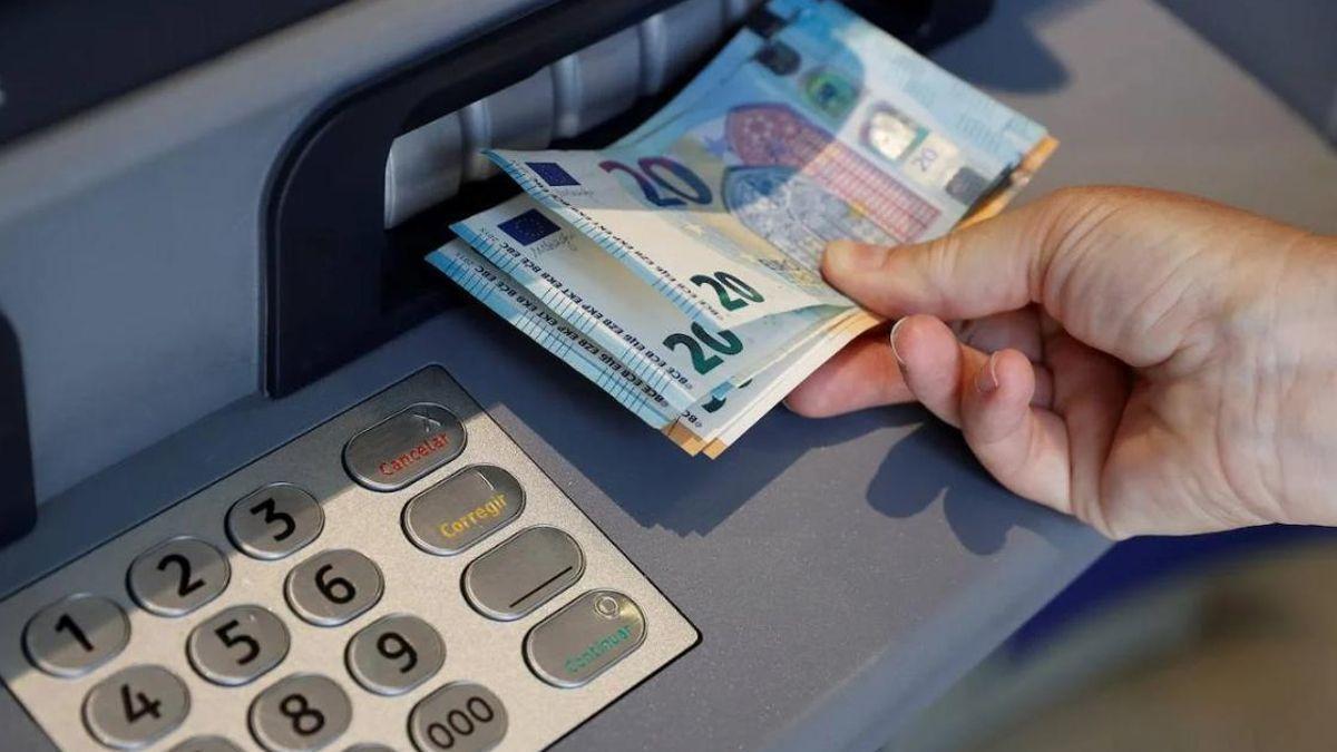 Una persona treu diners d'un caixer automàtic, en una imatge d'arxiu