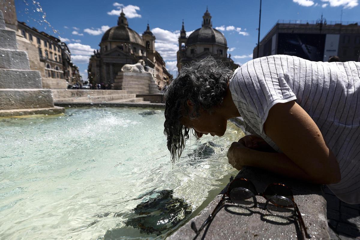 Una persona se refresca en una fuente.