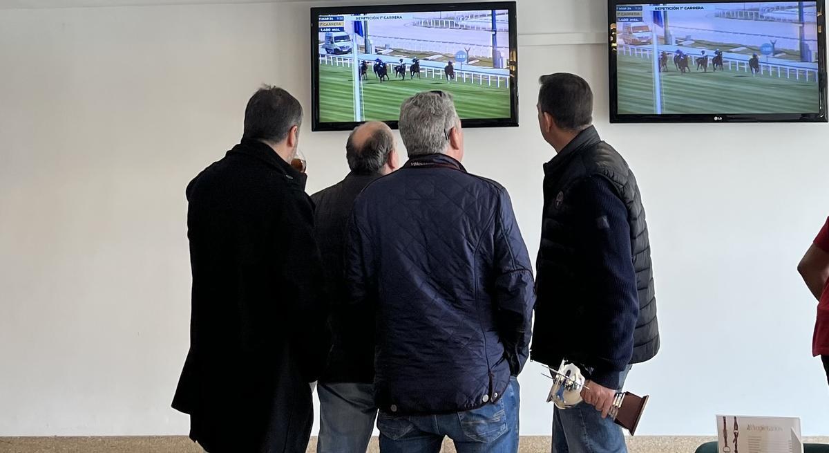 Un grupo de propietarios de una cuadra observa cómo ha sido la carrera en las pantallas del hipódromo