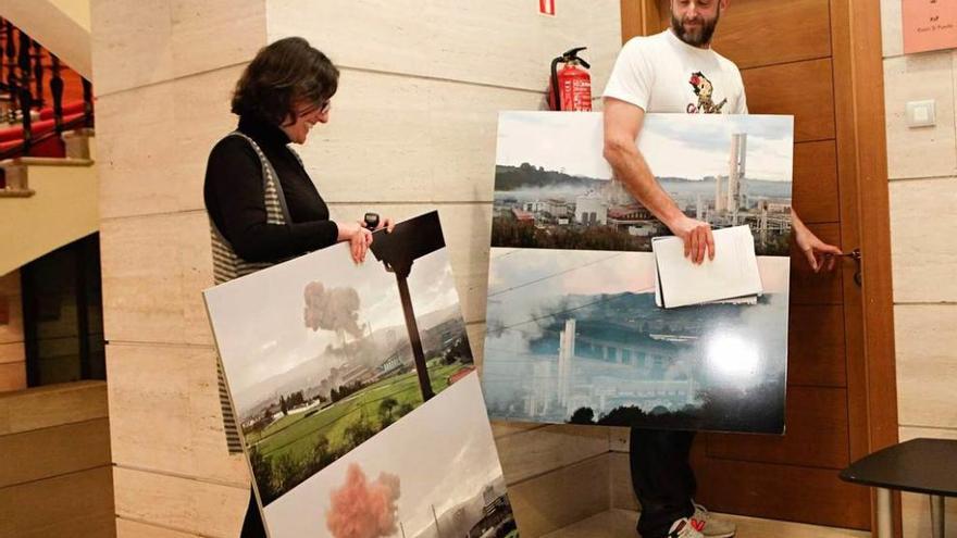 El concejal David Alonso, acompañado de Beatriz Viado, ante la puerta del despacho de Xixón Sí Puede con reproducciones de imágenes de nubes de contaminación sobre la ciudad.