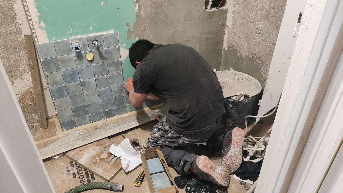 Un albañil realiza trabajos en el lavabo de una vivienda.