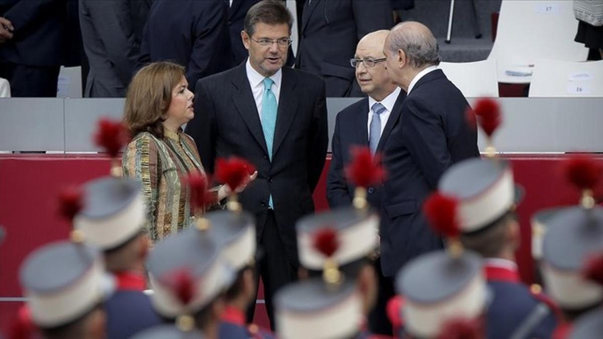 Cristóbal Montoro conversa con la vicepresidenta, Soraya Sáenz de Santamaría, y los ministros Rafael Catalá y Jorge Fernandez Diaz, durante el desfile del Día de la Hispanidad.