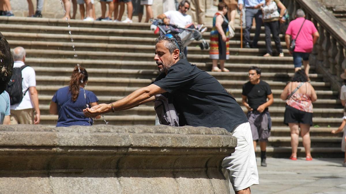 Un turista se refresca en la fuente de la plaza de las Platerías en Santiago