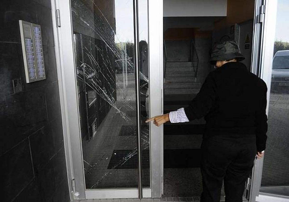 Una de las vecinas del edificio muestra desperfectos en el cristal de la puerta del edificio. / carlos pardellas
