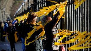 Varias personas colocan lazos amarillos en el parque de la Ciutadella de Barcelona