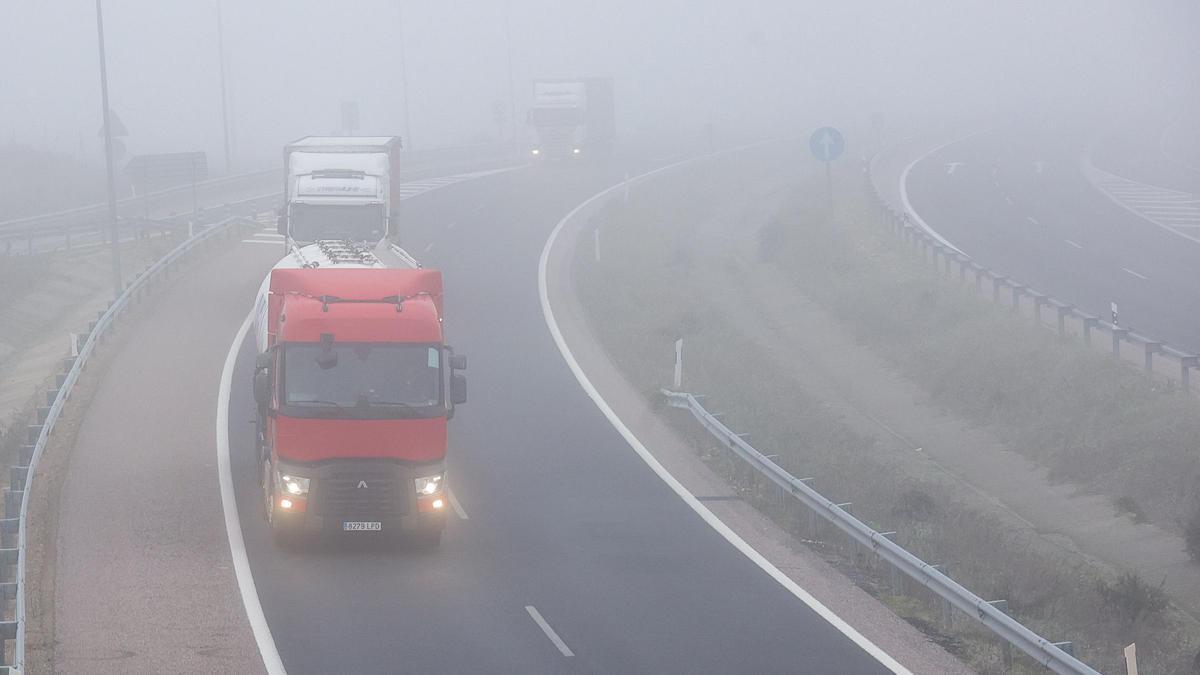 Camiones en un carretera con niebla.