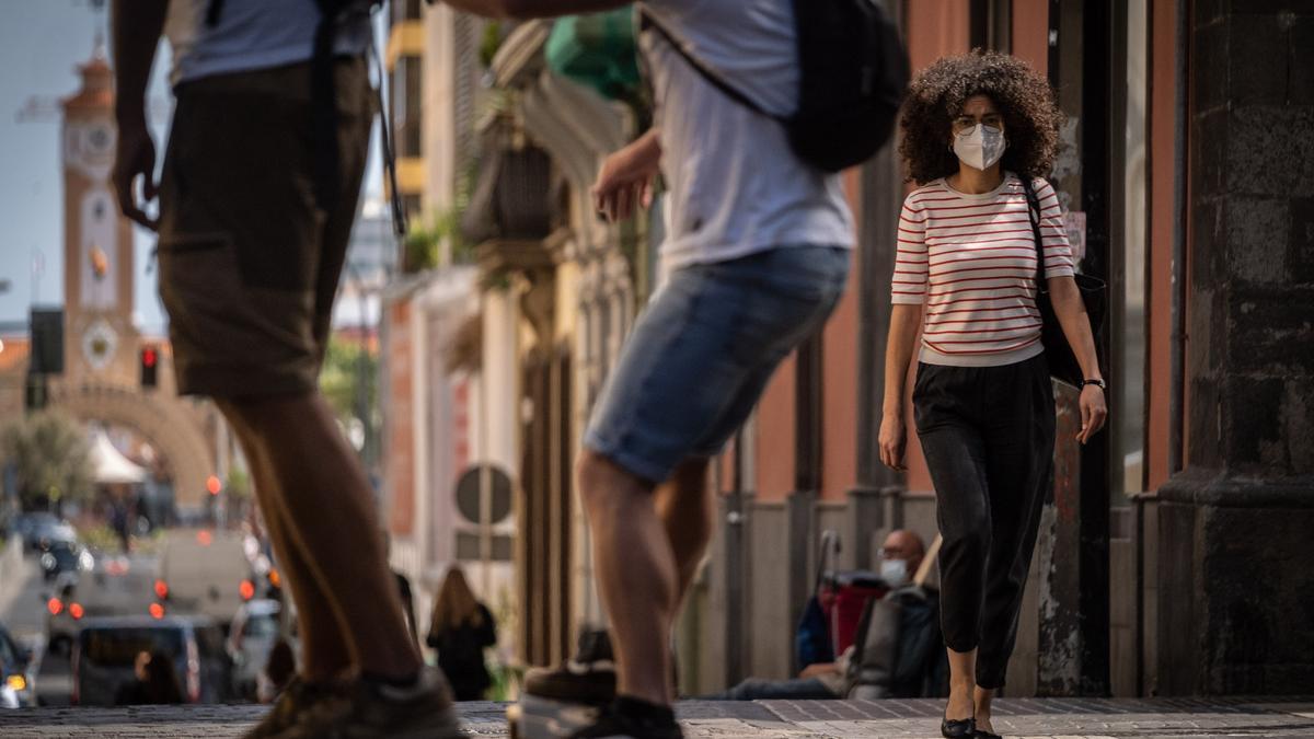 Una joven se cruza con dos skaters en el centro de Santa Cruz de Tenerife.