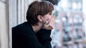 Una mujer preocupada, mirando por la ventana.