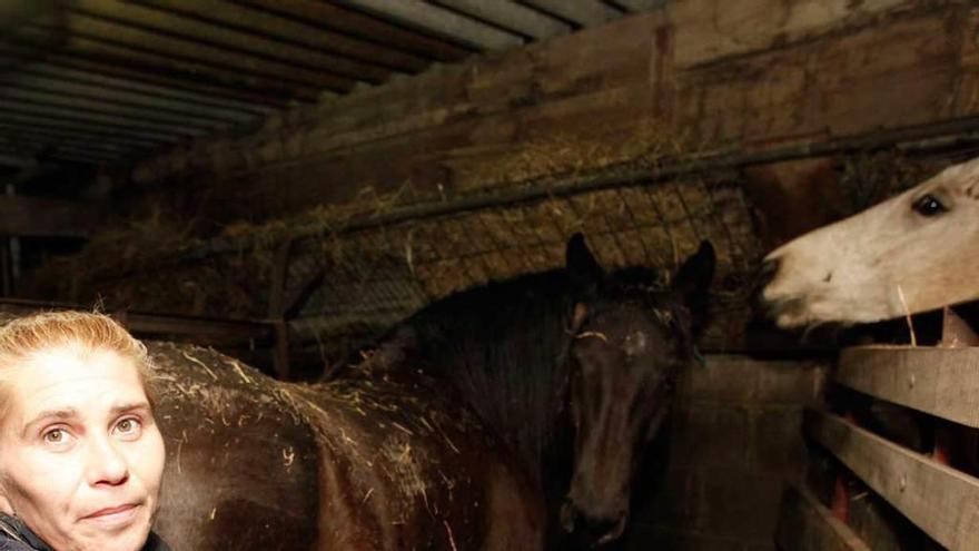 Eva María García, en la cuadra de su casa, con dos caballos.