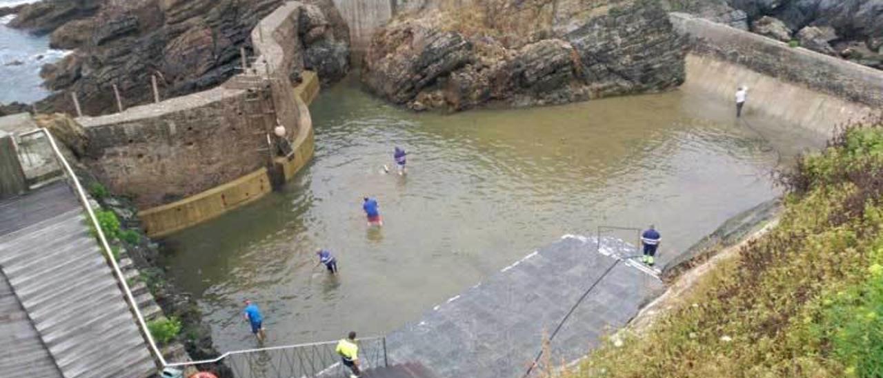 Operarios municipales trabajando ayer, a primera hora de la mañana, en la limpieza de la piscina.