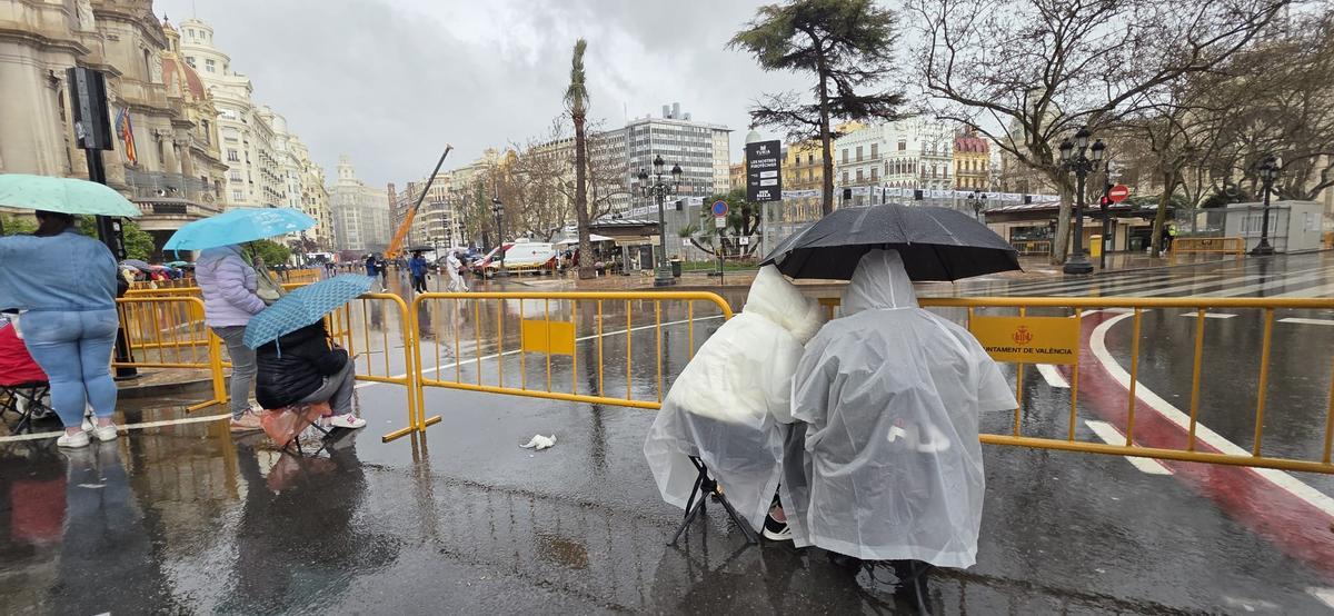 Aficionados a la "mascletà" aguardan estoicamente el final del chaparrón