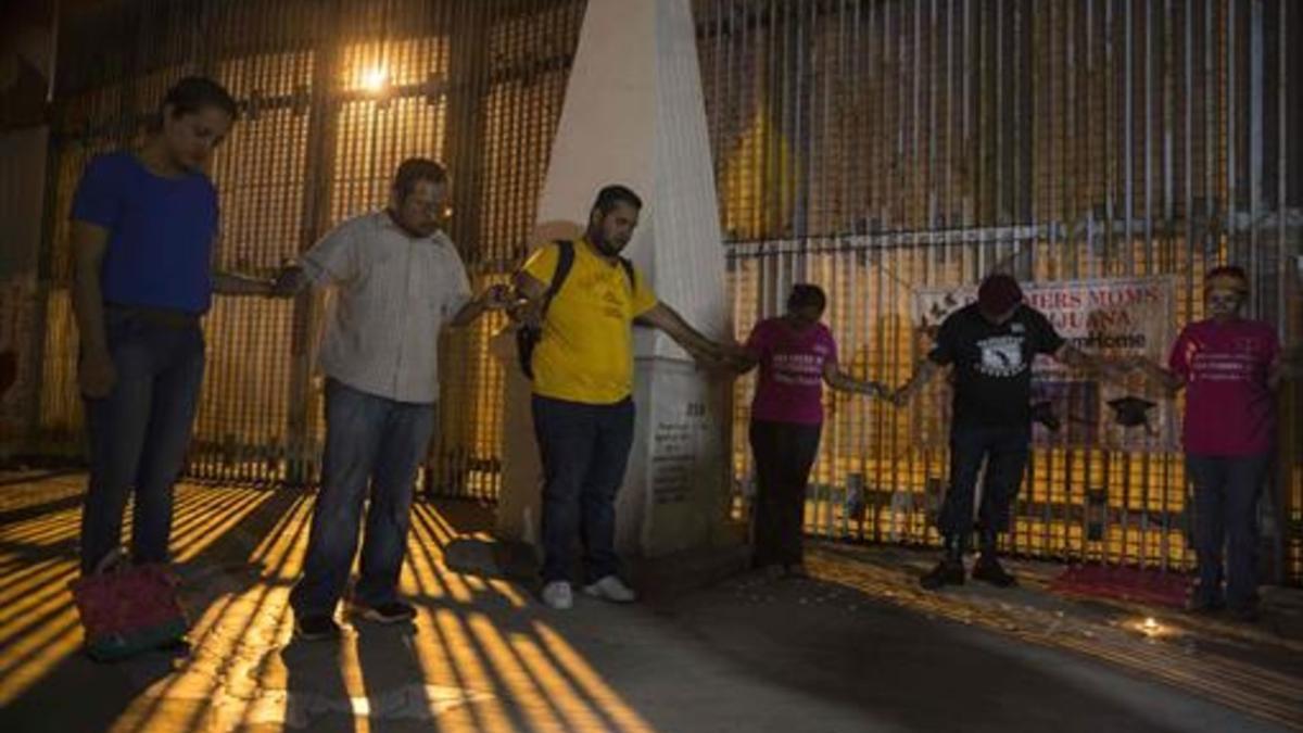 Un grupo de activistas reza ante el muro fronterizo entre EEUU y México en solidaridad con los 'dreamers'.