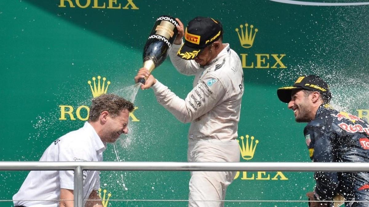 Lewis Hamilton ducha con champaña a uno de sus ingenieros en presencia de Danie de Ricciardo.