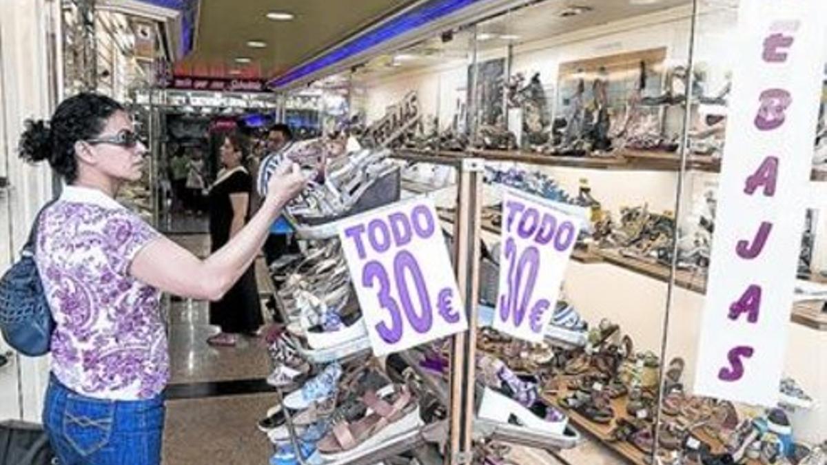 Campaña de verano 8Una mujer mira ofertas de zapatos rebajados en un comercio de Sants.