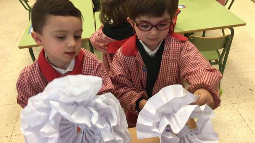 Dos escolares confeccionan flores gigantes para el homenaje a Lita Cabellut.  //