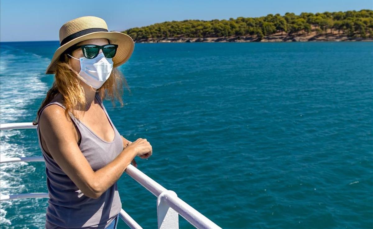 Una mujer viaja en barco, protegida con una mascarilla.