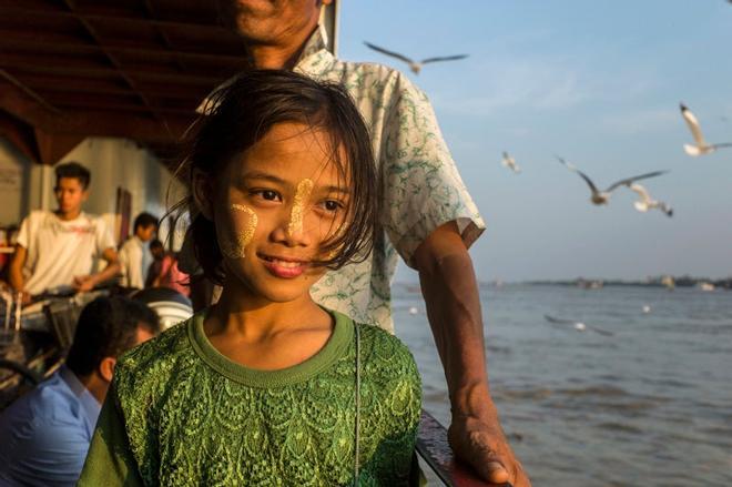 Niña en un ferri del río Ayeyarwady con la cara maquillada con thanaka