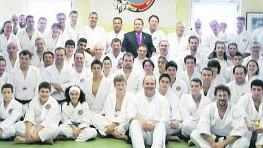 Foto de familia de los asistentes al curso mundial de tai-jitsu y a los exámenes de cinturón negro, con el presidente de la Federación Asturiana de Kárate en el centro.