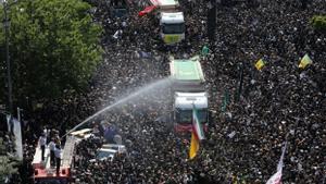 Bomberos iraníes rocían con agua a la multitud en el funeral del presidente Ebrahim Raisi en Teherán, Irán, este miércoles. 
