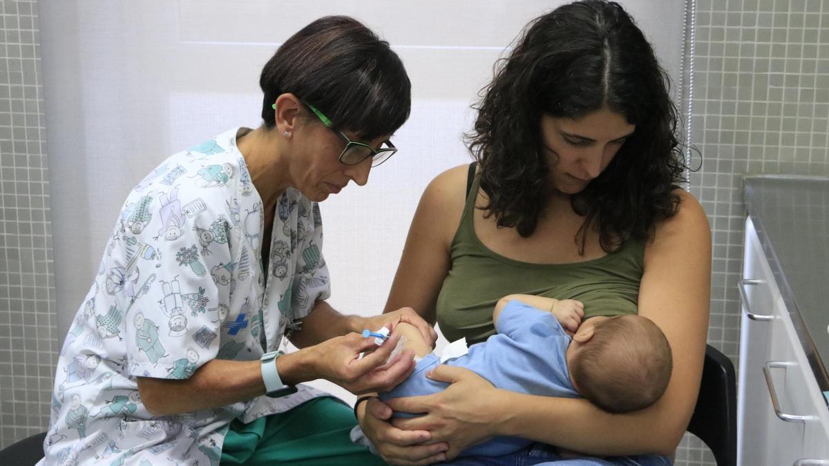 Una mare aguanta el seu nadó mentre el vacunen, en una foto d'arxiu