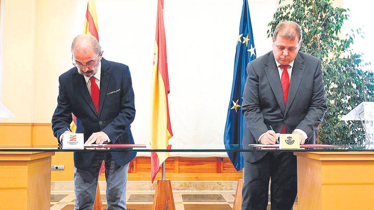 Los presidentes de Aragón y Correos, Javier Lambán y Juan Manuel Serrano, firman el acuerdo en el Pignatelli