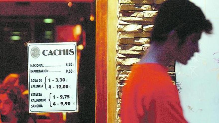 Un adolescente, ante un local de hostelería con un cartel anunciador de ofertas de bebidas.