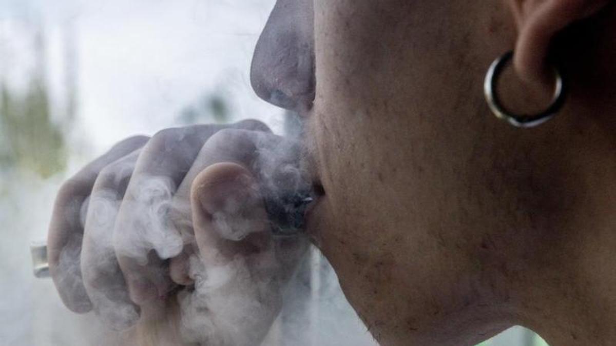 Un joven fuma mediante un dispositivo electrónico.