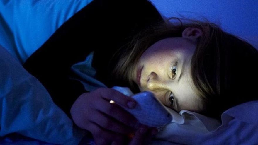 Una niña consulta el móvil antes de dormir.