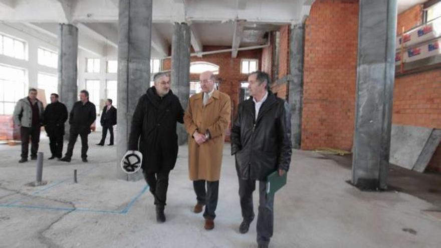 El alcalde (centro), flanqueado por los arquitectos del proyecto, en la planta de mercado.  //Jesús Regal