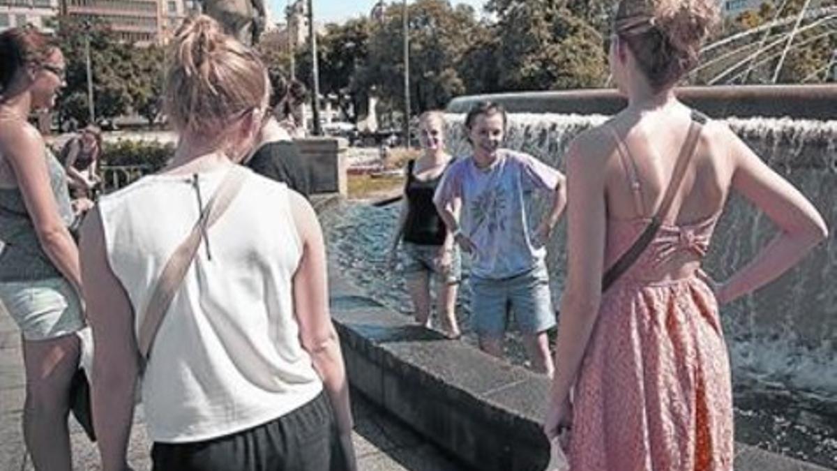 Unos paseantes se refrescan en una de las fuentes de la plaza de Catalunya, en Barcelona, ayer.